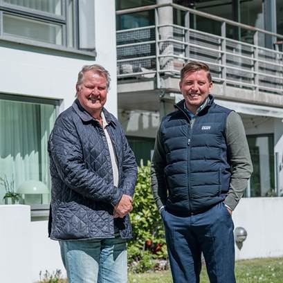 Styrelsemedlem i BRF Treudden och säljare från Öresundskraft framför bostadsrättsföreningen.