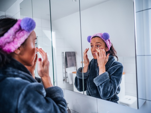 Kvinna i badrum och utför sin hudvårdsrutin