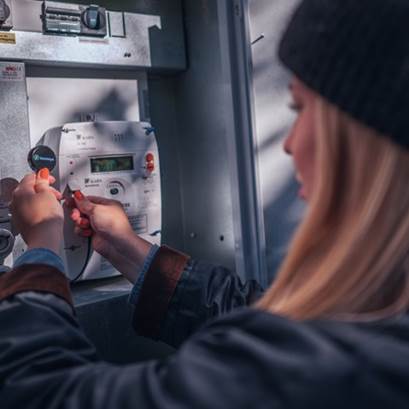 Kvinna ansluter realtidsmätare till elmätare