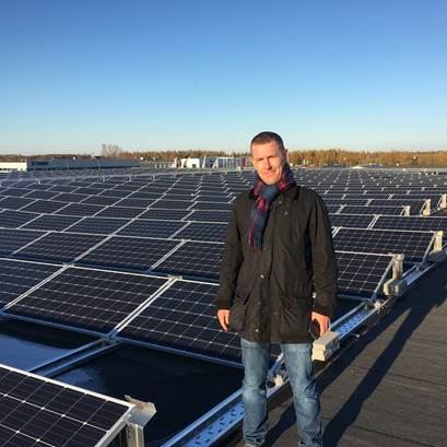 Man står på tak, med solceller i bakgrunden